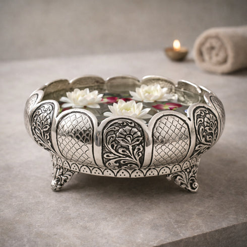 Decorative silver bowl with floral design on a gray surface
