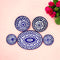 A set of blue and white ceramic dishes arranged on a pink background, featuring intricate geometric patterns in concentric medallions.