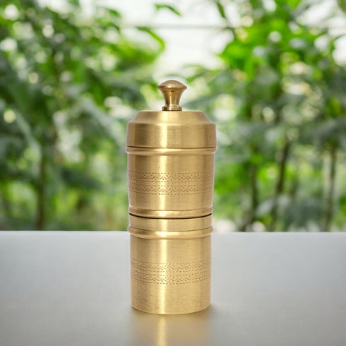 Brass grinder on a white surface with a blurred green background