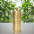 Brass grinder on a white surface with a blurred green background