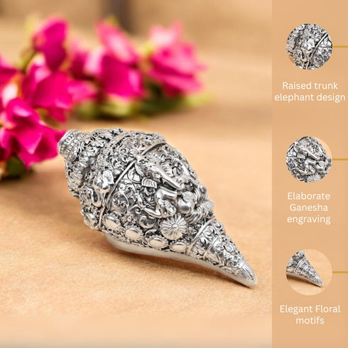 Decorative elephant trunk with Ganesha engraving and floral motifs on a beige background with pink flowers.