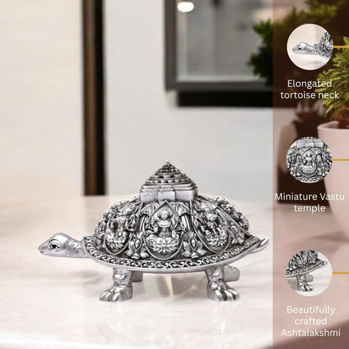 Decorative silver turtle statue with miniature Vastu temple on a white surface