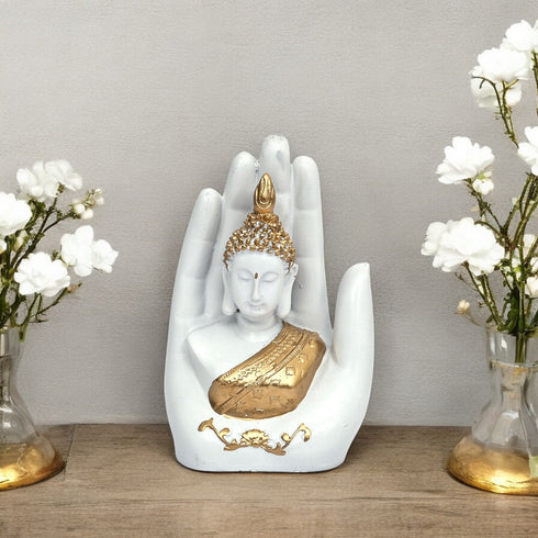 Decorative statue of a Buddha figure in a hand with white flowers on a wooden surface.