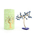 Decorative tree with colorful berries next to a green cylindrical container with a tree design.