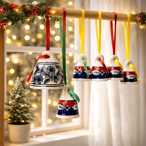 Decorative Christmas bells with colorful ribbons hanging on a wooden rod against a blurred festive background.