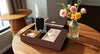 Decorative box with a photo frame, jewelry, and flowers on a wooden table.