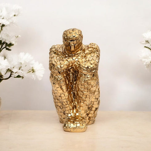 Gold mosaic sculpture on a neutral background with white flowers