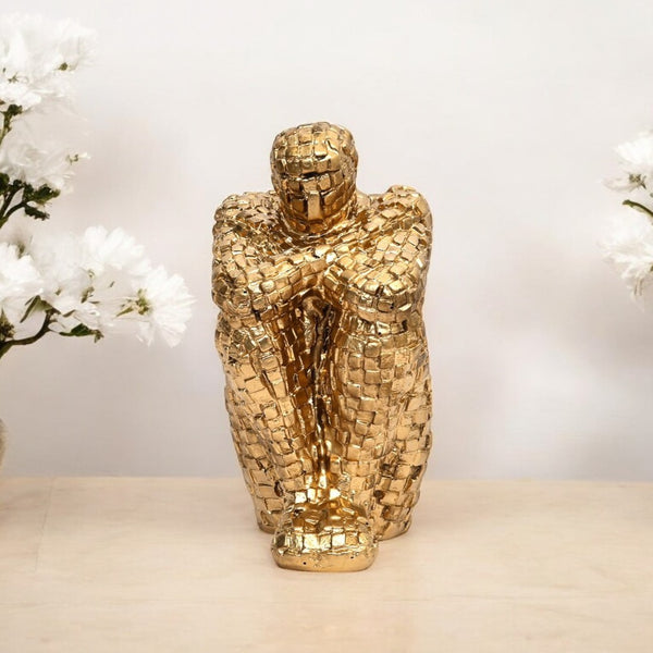 Gold mosaic sculpture on a neutral background with white flowers