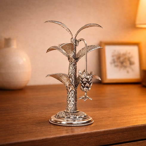 Decorative silver plant sculpture on a wooden surface with a blurred background