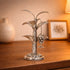 Decorative silver plant sculpture on a wooden surface with a blurred background