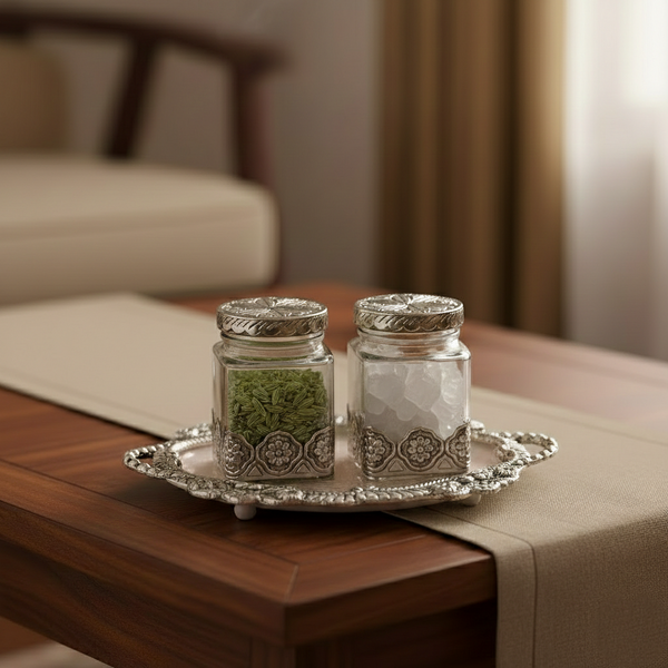 Two glass jars with silver lids on a decorative tray in a home setting.