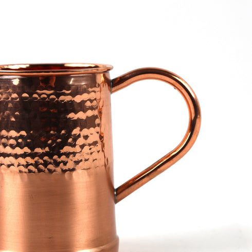 Close-up of a hammered copper mug with a polished handle on a white background.