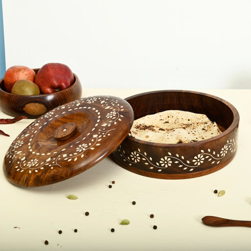 Wooden bowl with lid containing flatbread, surrounded by fruits and spices on a light background