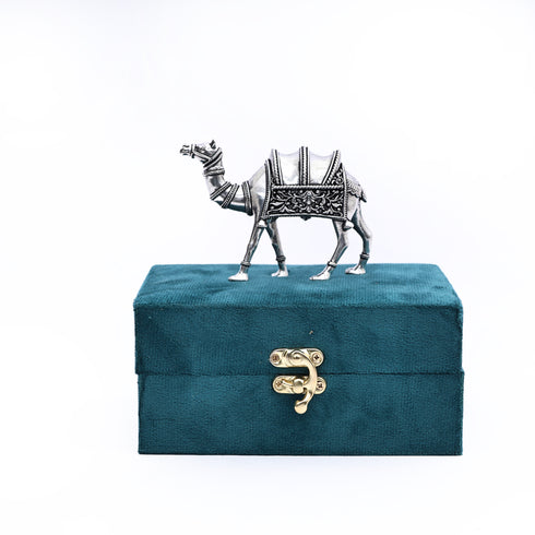 Teal jewelry box with a decorative camel on top against a white background