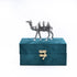 Teal jewelry box with a decorative camel on top against a white background