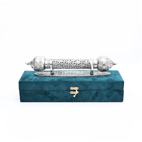 Decorative silver object on a teal box with a white background