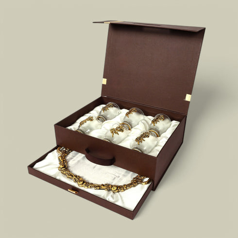 Open brown jewelry box with gold jewelry on a beige background