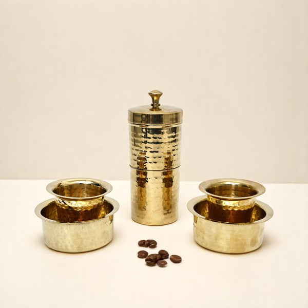 Set of gold-colored metal containers on a white surface with a beige background
