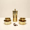 Set of gold-colored metal containers on a white surface with a beige background