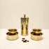 Set of gold-colored metal containers on a white surface with a beige background