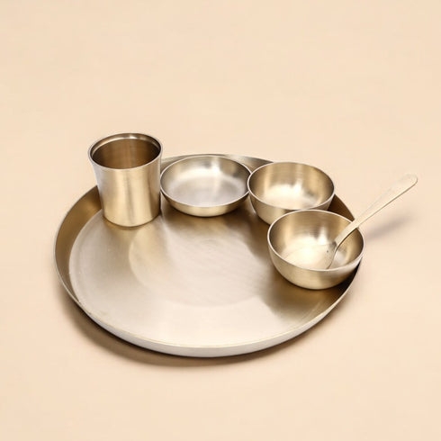 Set of metallic bowls and a cup on a beige background