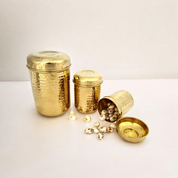 Set of three hand-hammered brass containers, with one container open displaying small items inside, all placed on a white surface.