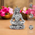 Silver-plated statue in meditative pose with decorative flowers in the background