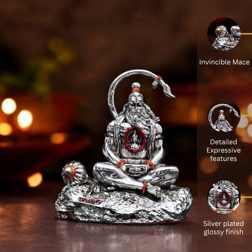 Silver statue with detailed features on a reflective surface, blurred lights in the background