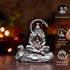 Silver statue with detailed features on a reflective surface, blurred lights in the background