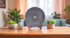 Decorative plate on a stand with plants on a wooden table in a home setting