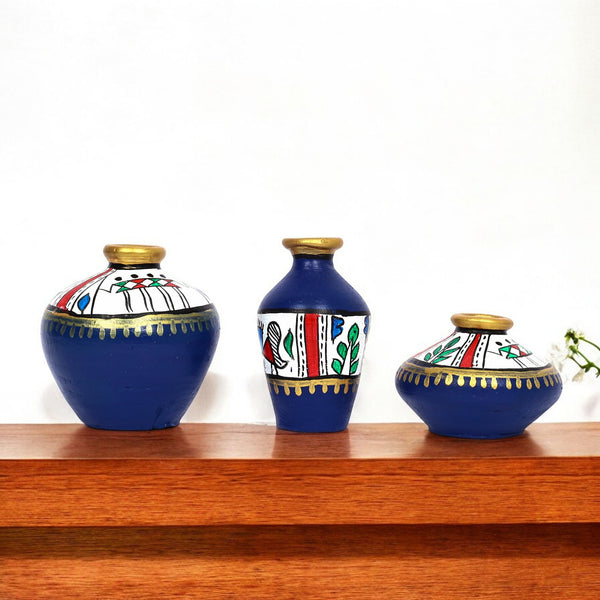 Three decorative vases with blue, white, and gold patterns on a wooden shelf.