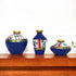 Three decorative vases with blue, white, and gold patterns on a wooden shelf.