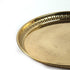 A close-up of a round brass tray with a fluted rim and an engraved floral pattern on the surface, set against a plain white background.