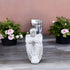 White stone angel statue on a wooden surface with potted plants in the background