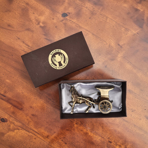 Brass horse-drawn carriage figurine in a Natriel box on a wooden surface