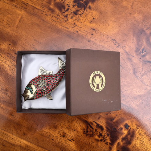 Decorative fish-shaped object in a Natafel box on a wooden surface