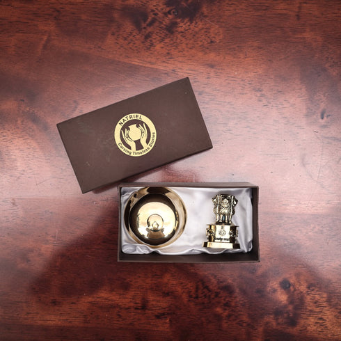 Two gold items in a box with a brand logo on a wooden surface