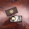 Two gold items in a box with a brand logo on a wooden surface
