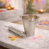 Decorative silver cup and piping bag on a marble surface with colorful powder in the background