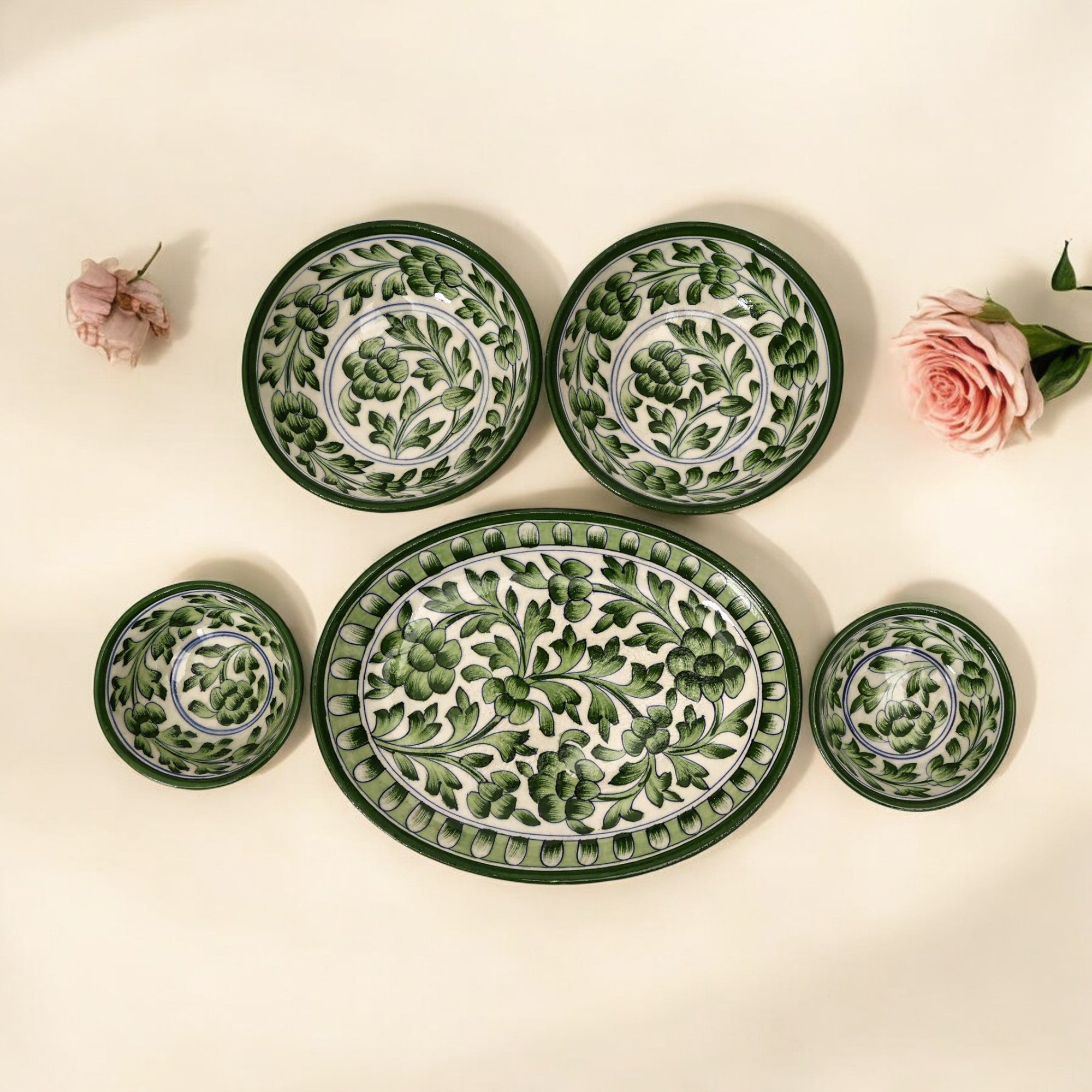 A set of handcrafted green floral pottery including an oval platter and two bowls, with a traditional pattern of green floral motifs on a white background.