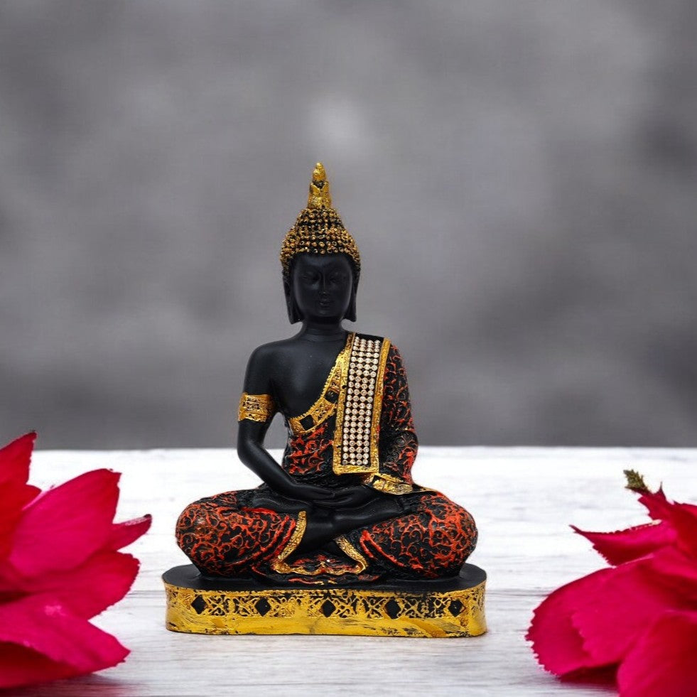 Black Buddha statue with gold and red details on a gray background with pink flowers.