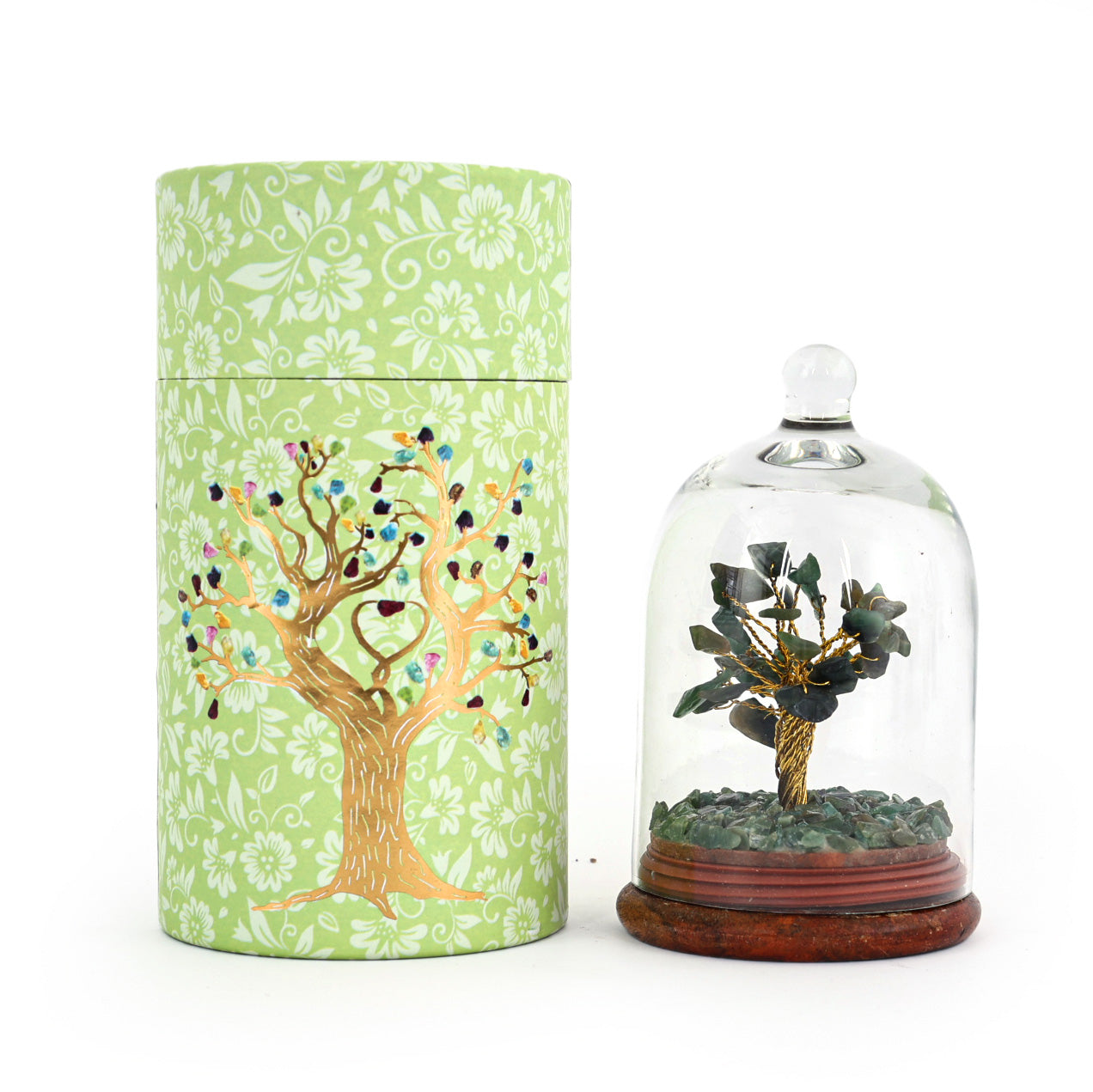 Decorative container with tree design next to a small tree in a glass dome on a white background