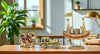 Decorative items including a gold elephant, car, and decorative ship on a wooden surface with a plant and books in the background.