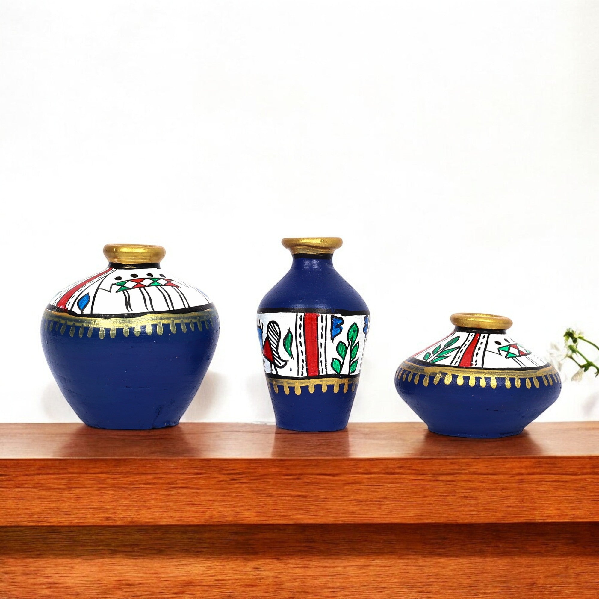 Three decorative vases with blue, white, and gold patterns on a wooden shelf.