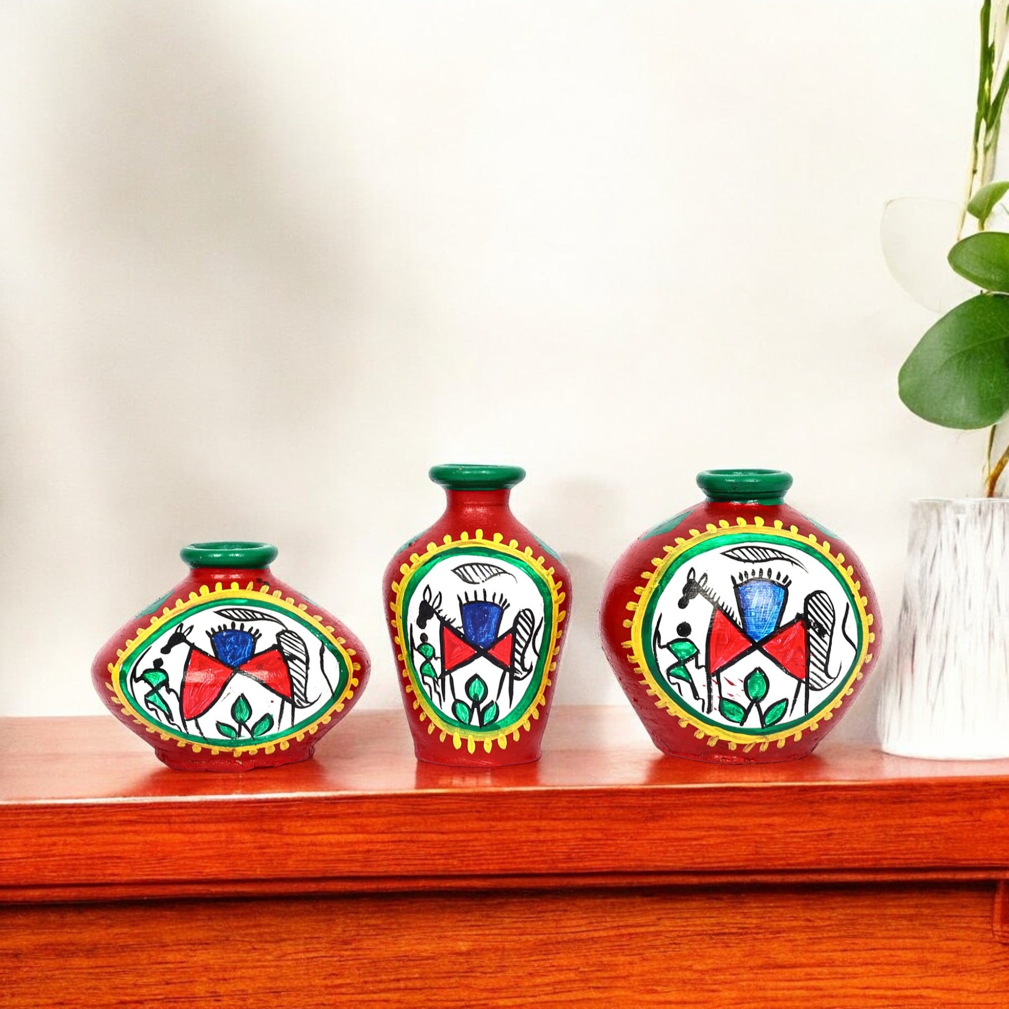 Three decorative vases with colorful patterns on a wooden surface.